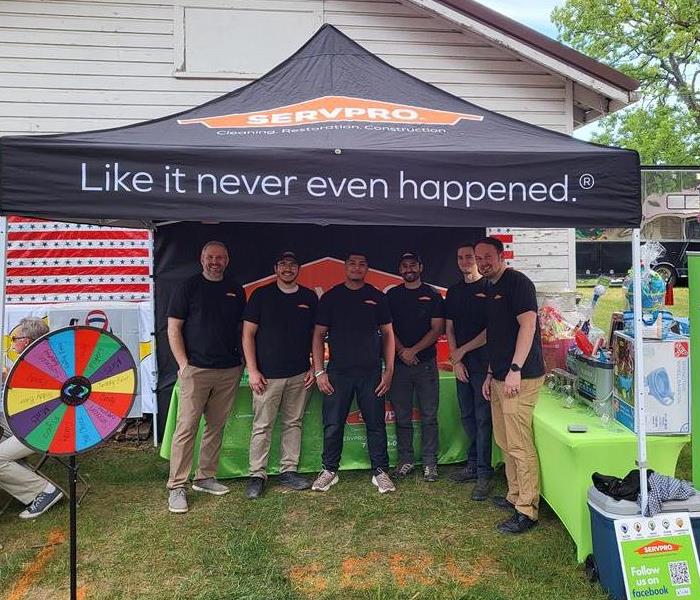 A group of six men stand together smiling in their SERVPRO gear.