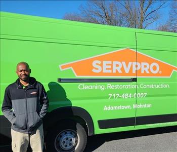 A new SERVPRO employee stands in front of a green SERVPRO van.
