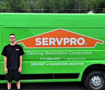 Employee Alec Stoner standing next to the green SERVPRO Promaster Van